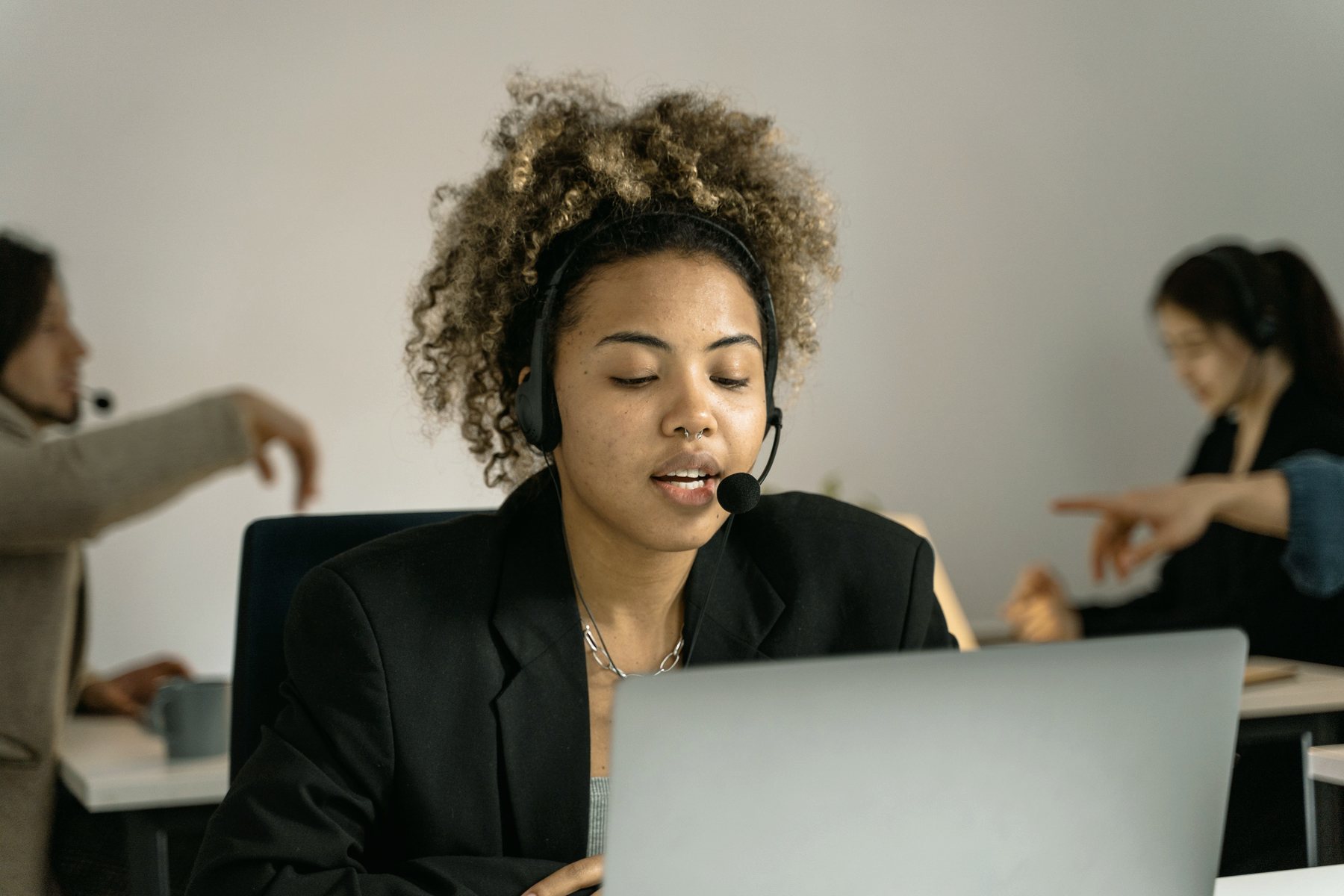 A customer support agent wearing a headset and working at a laptop.