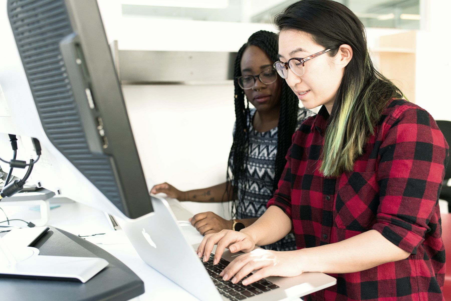 Two developers working through a problem together at a monitor.