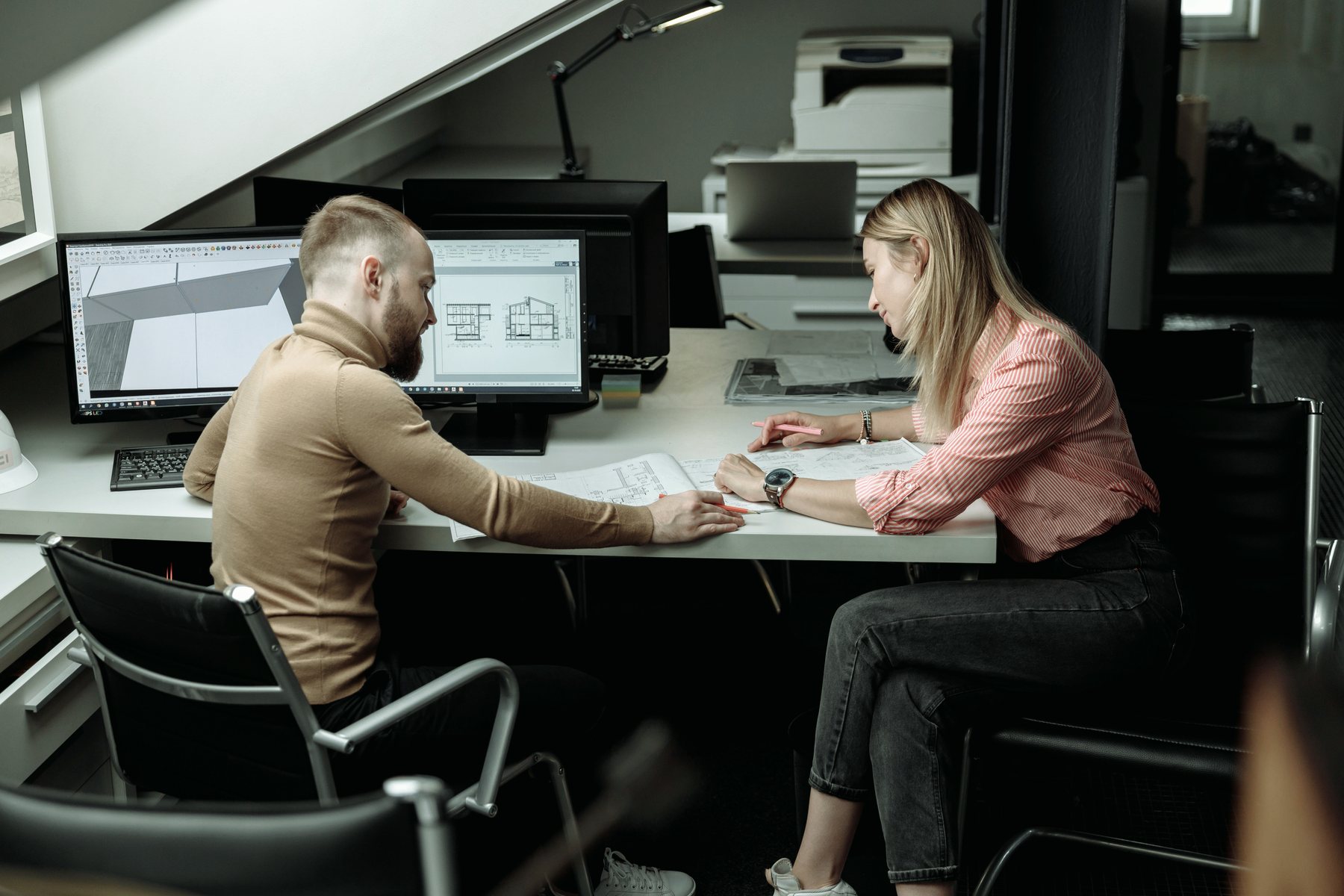 Two architects going through drawings together at a desk.
