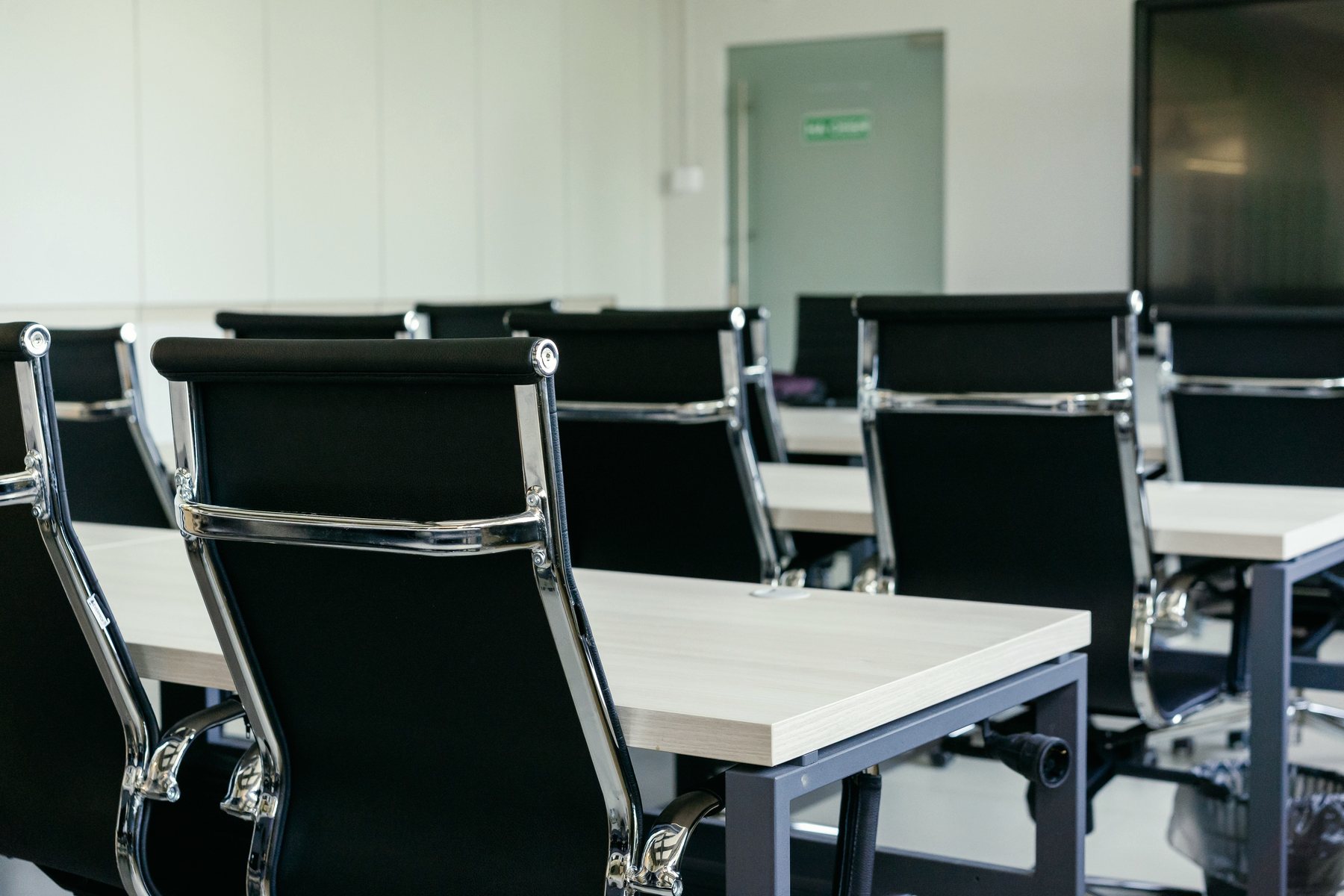 An empty meeting room, chairs pushed in around a bare table.