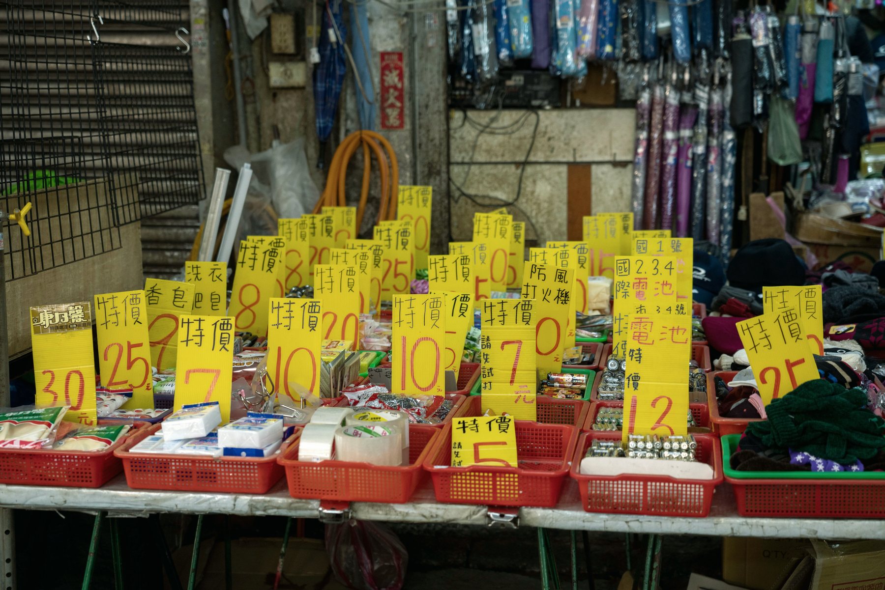 A market stall crowded with goods under bright hand-written price tags.