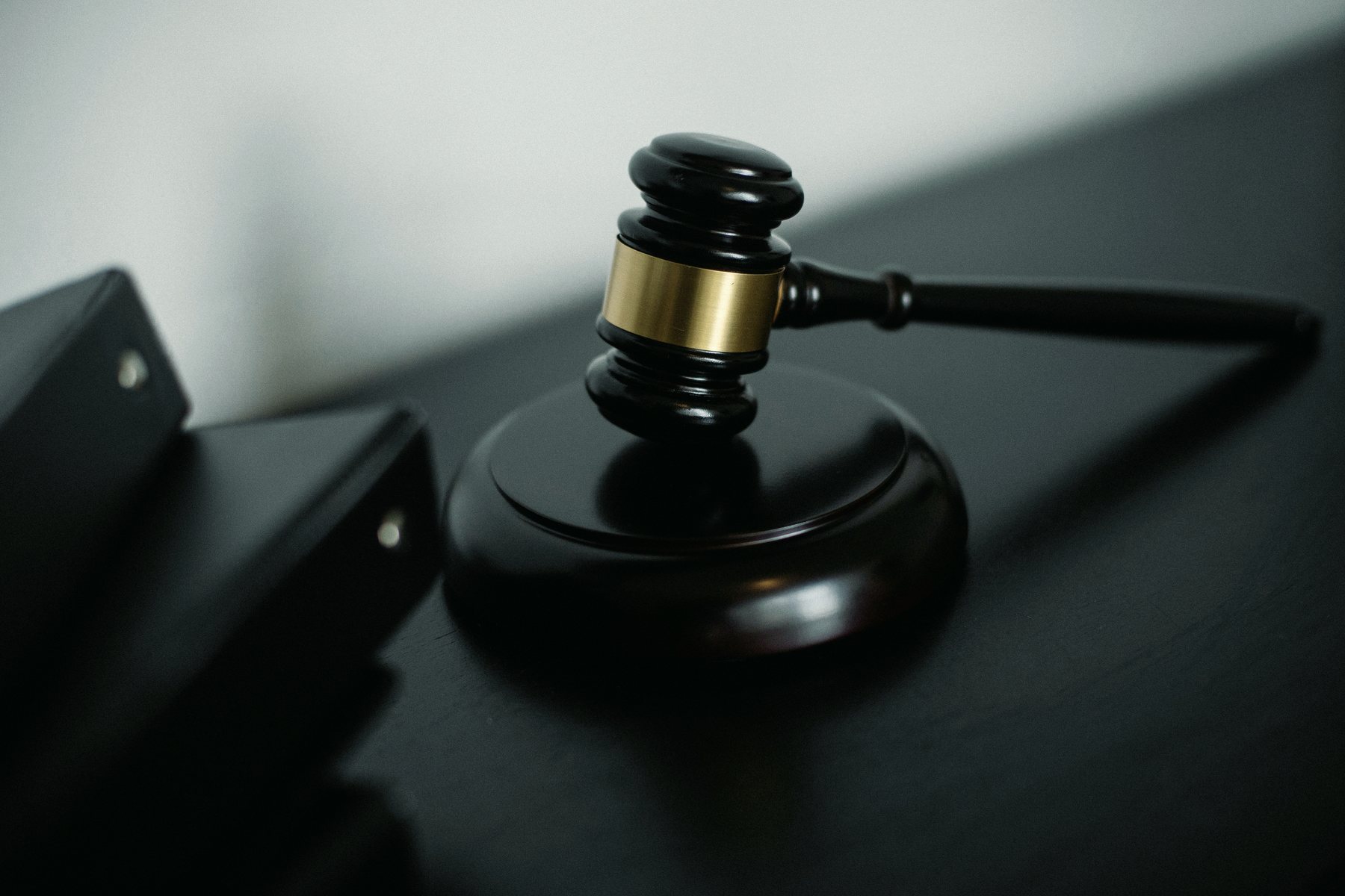 A dark wooden gavel with a brass band resting on its sounding block.